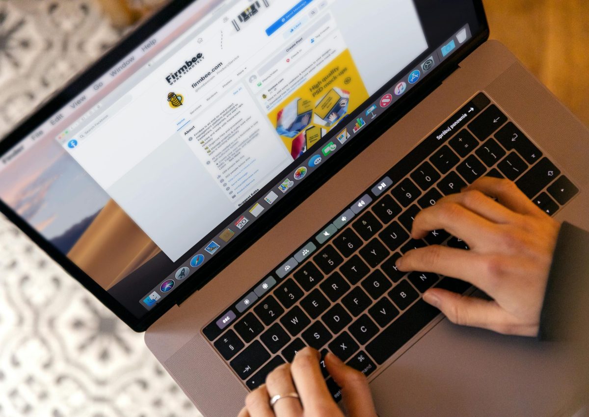 Hands typing on a laptop at a desk, engaging in online work, and navigating social media.