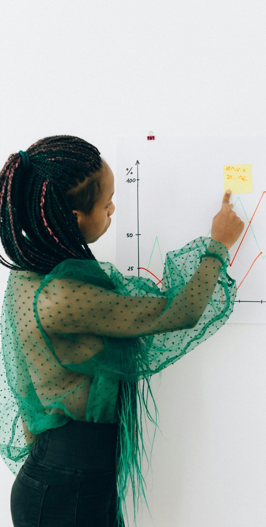 Focused woman points to financial graph, showcasing analysis & strategy.